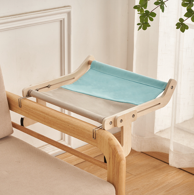 No-Suction Wooden Cat Window Perch - Heavy-Duty Adjustable Hook-On Shelf & Safety Sun Lounger with natural wood frame and pastel blue and beige fabric support, attached to a wooden bed frame near a window.