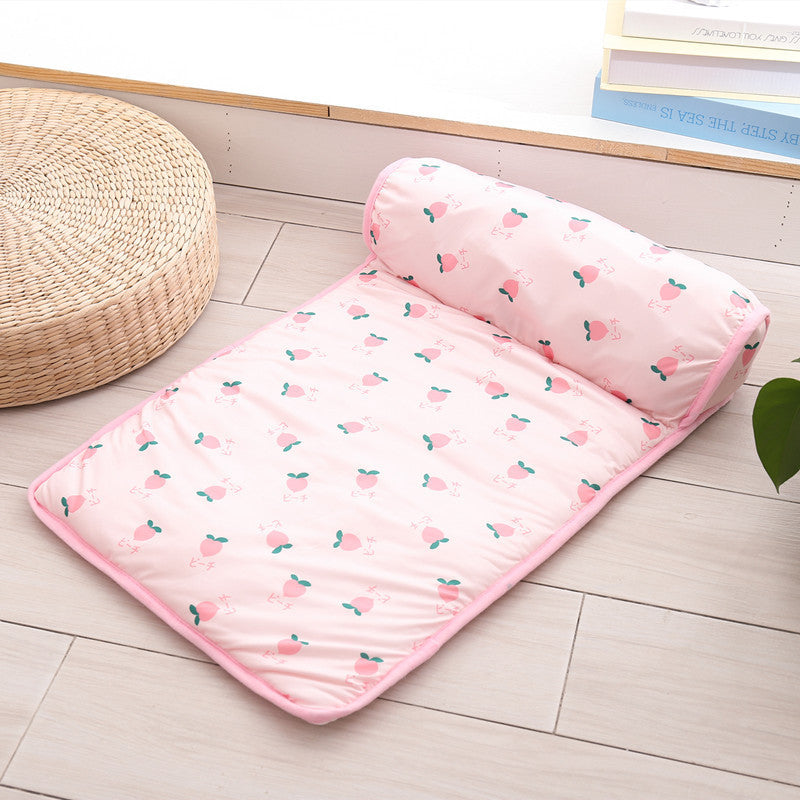 Pink patterned Boutique Ice-Silk Cooling Mat - Patterned Heatstroke Prevention Sleeping Bed laid out on a wooden floor next to a woven round cushion and books.
