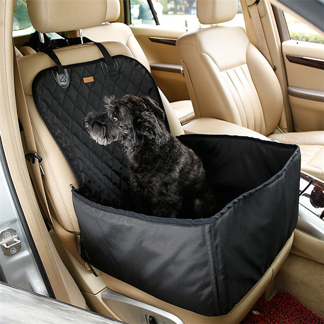 Small black dog sitting comfortably in a Heavy-Duty Dog Car Booster Seat - Waterproof & Nonslip Safety Basket for Front or Back Seat placed on the beige front passenger car seat.
