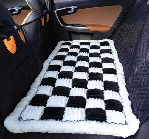 Designer Checkered Travel Dog Bed - Thickened Quilted Car Seat Mat - Nonslip Portable Pet Sleeping Pad in black and white checkered pattern placed on the back seat of a car.