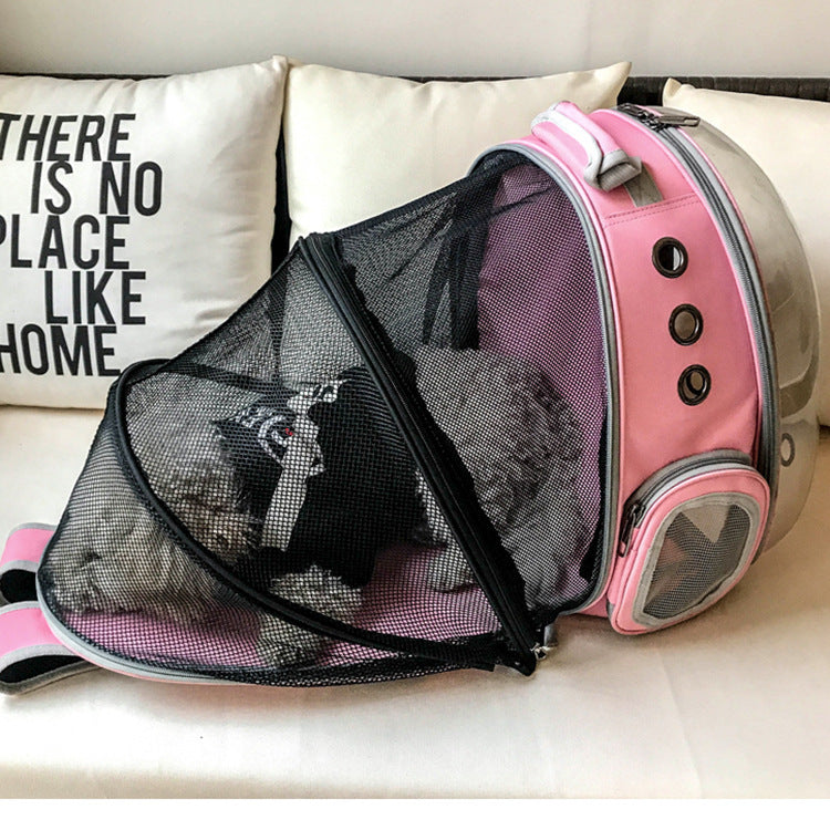 Small dog resting inside a pink and white Panoramic Expandable Space Capsule - Premium Pet Travel Backpack with a mesh front and transparent side bubble, placed on a sofa near a decorative pillow.