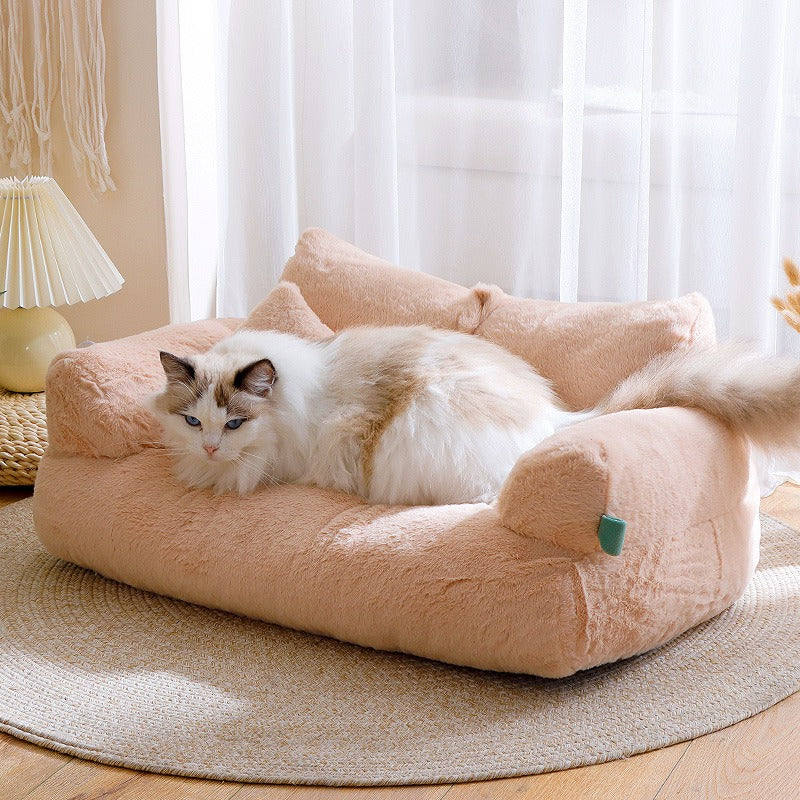 White and tan cat resting comfortably on a soft beige Orthopedic Calming Pet Sofa - Luxury Plush Dog & Cat Bed Couch with Bolster Support placed on a round woven rug in a cozy room.
