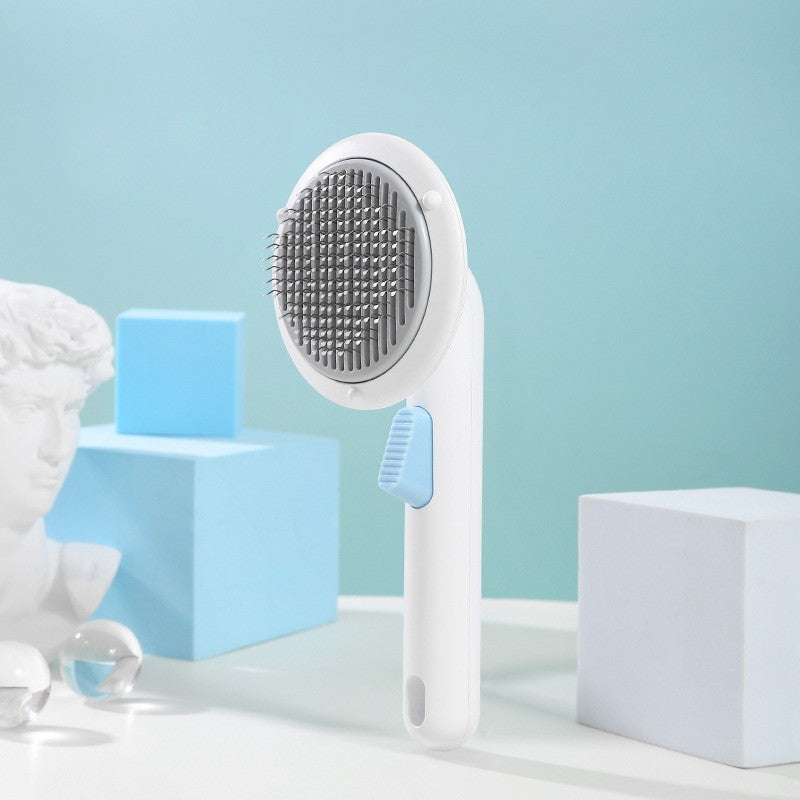 Boutique Pumpkin Self-Cleaning Brush - Aesthetic Grooming & Deshedding Comb in white with blue button, shown against a modern pastel backdrop with sculptural and geometric elements.
