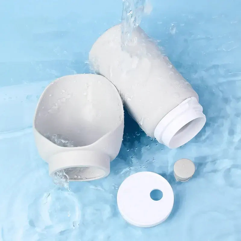 Soft Silicone Ultra-Compact Dispenser – 550ml Lightweight Minimalist Travel Bottle shown disassembled under running water, highlighting easy-clean design and soft silicone material.