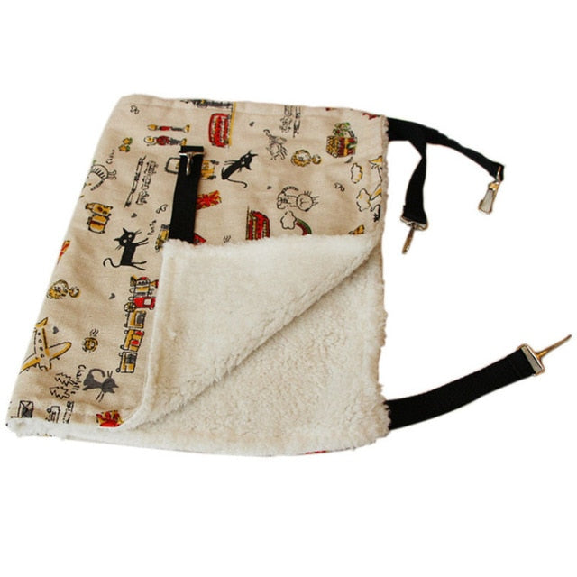 Thermal Hanging Cat Hammock - Double-Sided Winter Warm Fleece Bed for Cages, Crates & Chairs with soft white fleece interior and beige fabric exterior decorated with playful cat and toy illustrations.