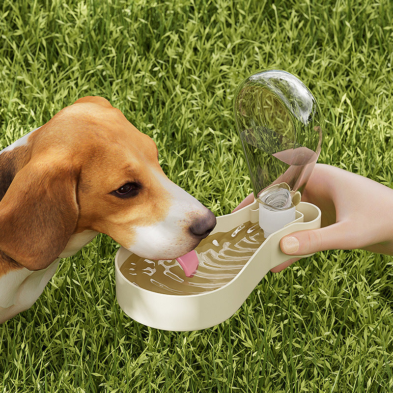 A dog drinking water from a portable water dispenser outdoors on grass, featuring the 2-Layer Pet Travel Station – Dual-Chamber Portable Feeder designed for convenient pet hydration and feeding on the go.