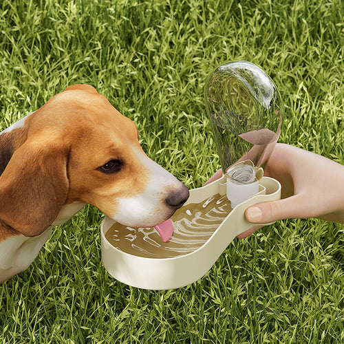 A dog drinking water from a portable water dispenser outdoors on grass, featuring the 2-Layer Pet Travel Station – Dual-Chamber Portable Feeder designed for convenient pet hydration and feeding on the go.