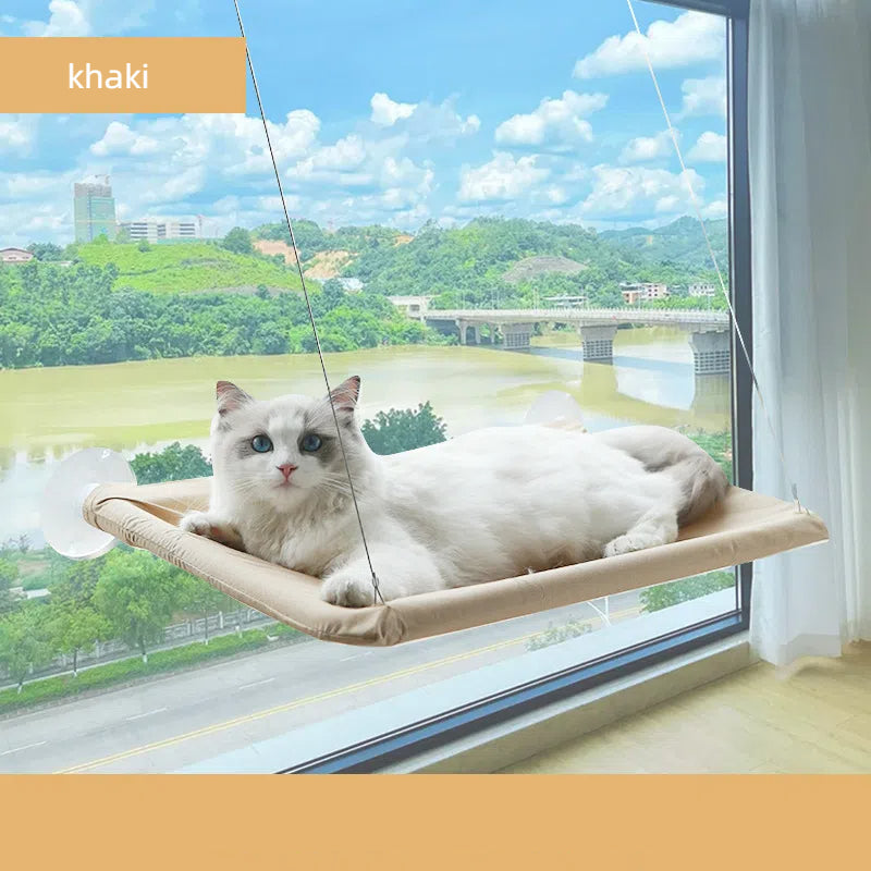 White cat lounging on a khaki Foldable Cat Window Hammock - Space-Saving Suction Cup Perch & Elevated Sunbed attached to a large window with a scenic view.