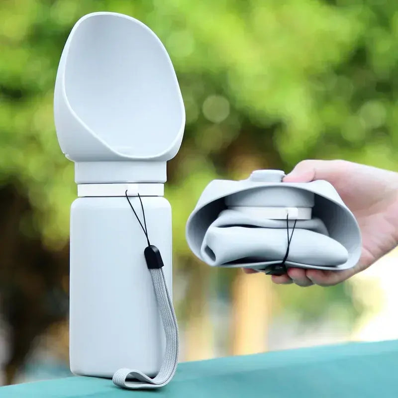 Soft Silicone Ultra-Compact Dispenser – 550ml Lightweight Minimalist Travel Bottle shown both expanded for use and folded compactly in hand outdoors with green blurred background.