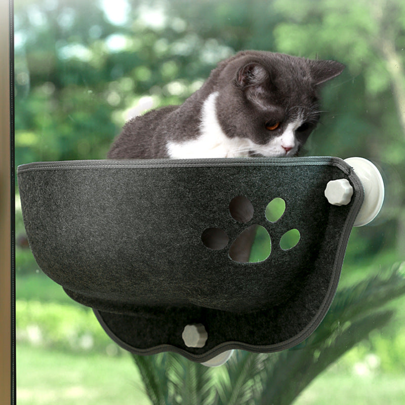 Cat resting inside a dark gray felt pod mounted on a glass window with suction cups, featuring a paw-print cutout, showcasing the Luxury Felt Cat Window Pod - Designer Glass-Mounted Sun Lounger & Private Hideaway.