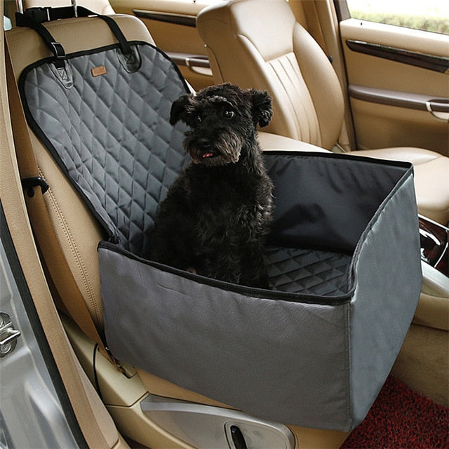 Small black dog sitting comfortably in a gray Heavy-Duty Dog Car Booster Seat - Waterproof & Nonslip Safety Basket for Front or Back Seat installed on a tan leather car seat, providing secure and cushioned travel space.