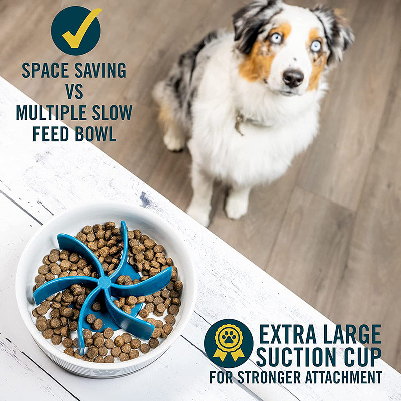 Top view of a dog food bowl fitted with the Universal Propeller Slow Feeder Insert - Spiral Anti-Gulping Solution, showing the blue spiral insert with dry kibble and text highlighting space-saving design and an extra large suction cup for strong attachment, with a dog in the background.