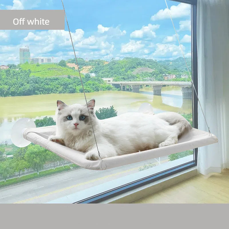 White cat lounging comfortably on a Foldable Cat Window Hammock - Space-Saving Suction Cup Perch & Elevated Sunbed attached to a window with a scenic outdoor view.