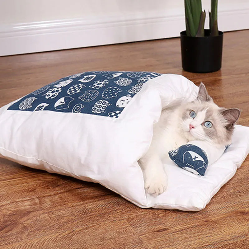 A fluffy cat comfortably resting inside the Deep-Sleep Cat Sleeping Bag - Self-Warming Burrower Bed & Thermal Hideaway with a cozy patterned cover on a wooden floor near a potted plant.