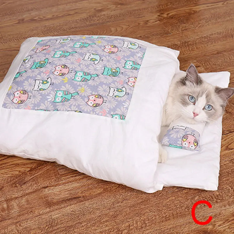 A white cat with blue eyes resting on a wood floor, partially covered by a white sleeping bag featuring a colorful owl print, showcasing the Deep-Sleep Cat Sleeping Bag - Self-Warming Burrower Bed & Thermal Hideaway.
